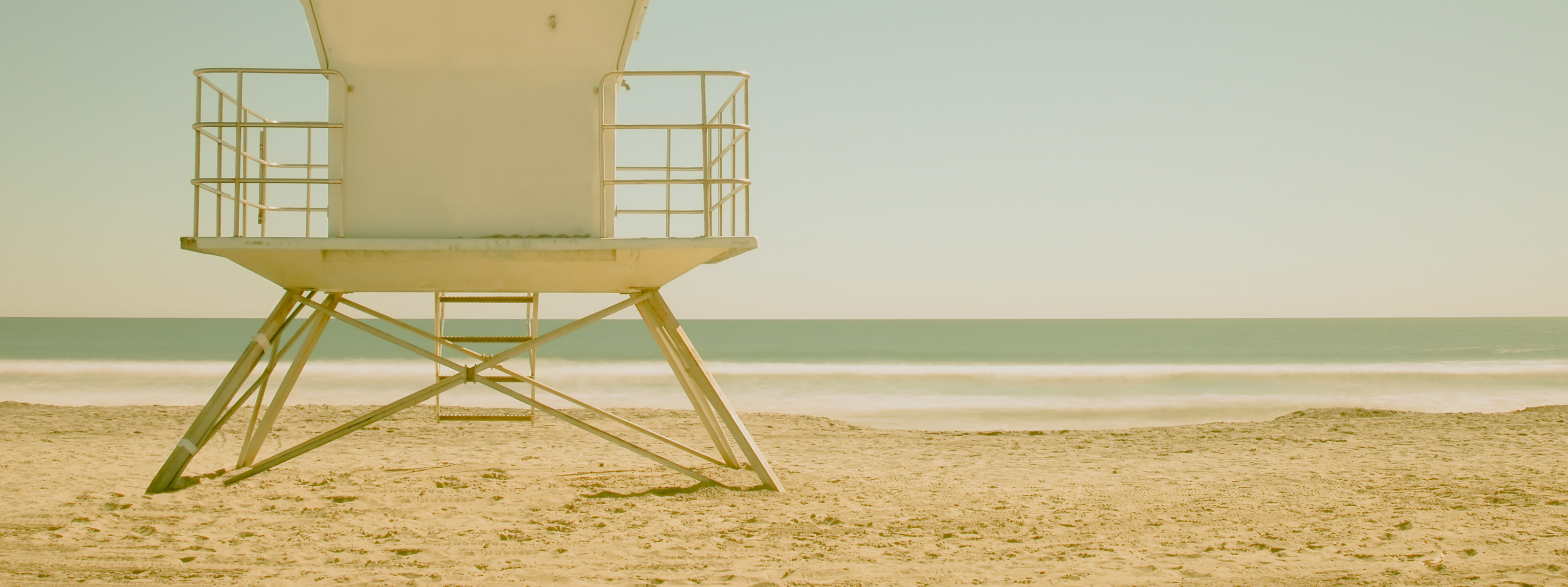 The best Bitcoin Swimwear at the Orange Habit Image of a Lifeguard tower on a sandy beach with a clear sky